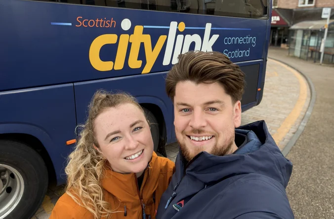 Man and woman stand in front of a Citylink coach.