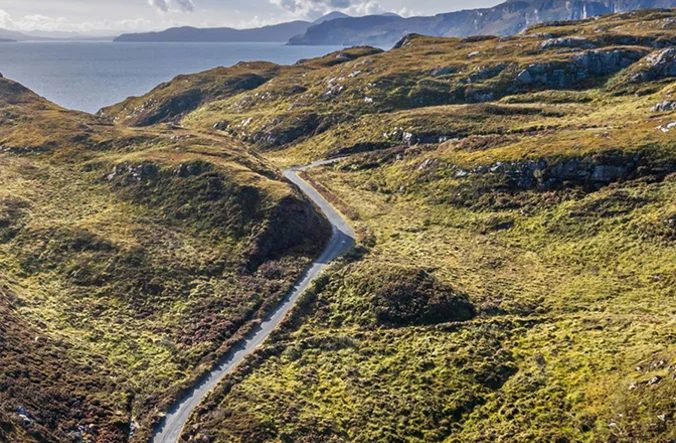 Aerial shot of a road running through Scottish landscape.