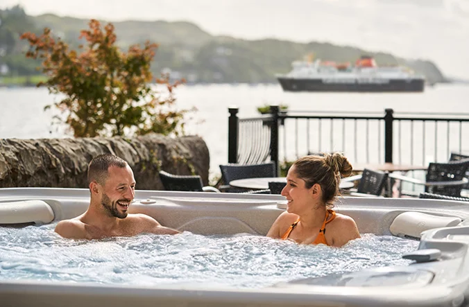 Couple enjoying an outdoor hot tub at Oban Bay Hotel