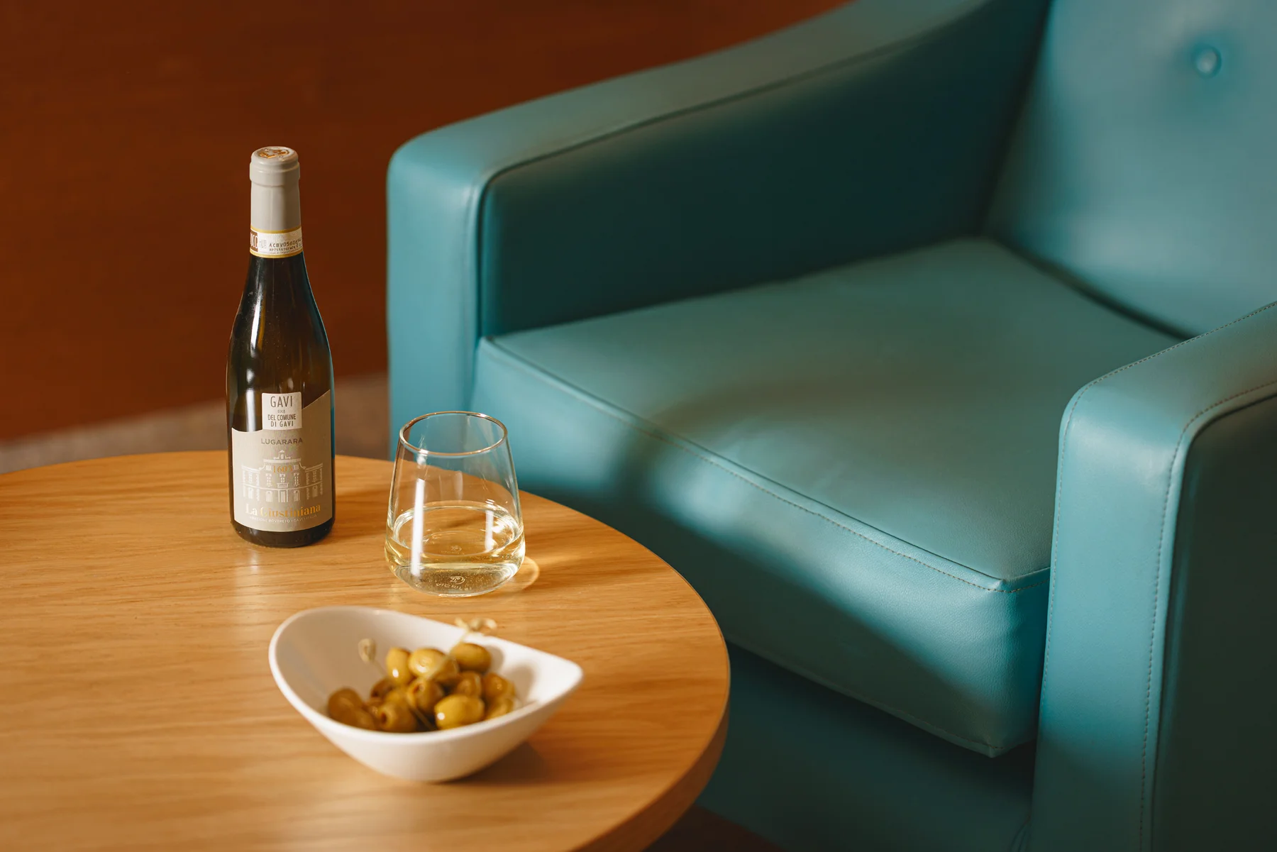 Bottle and glass of white wine with a side of olives. 