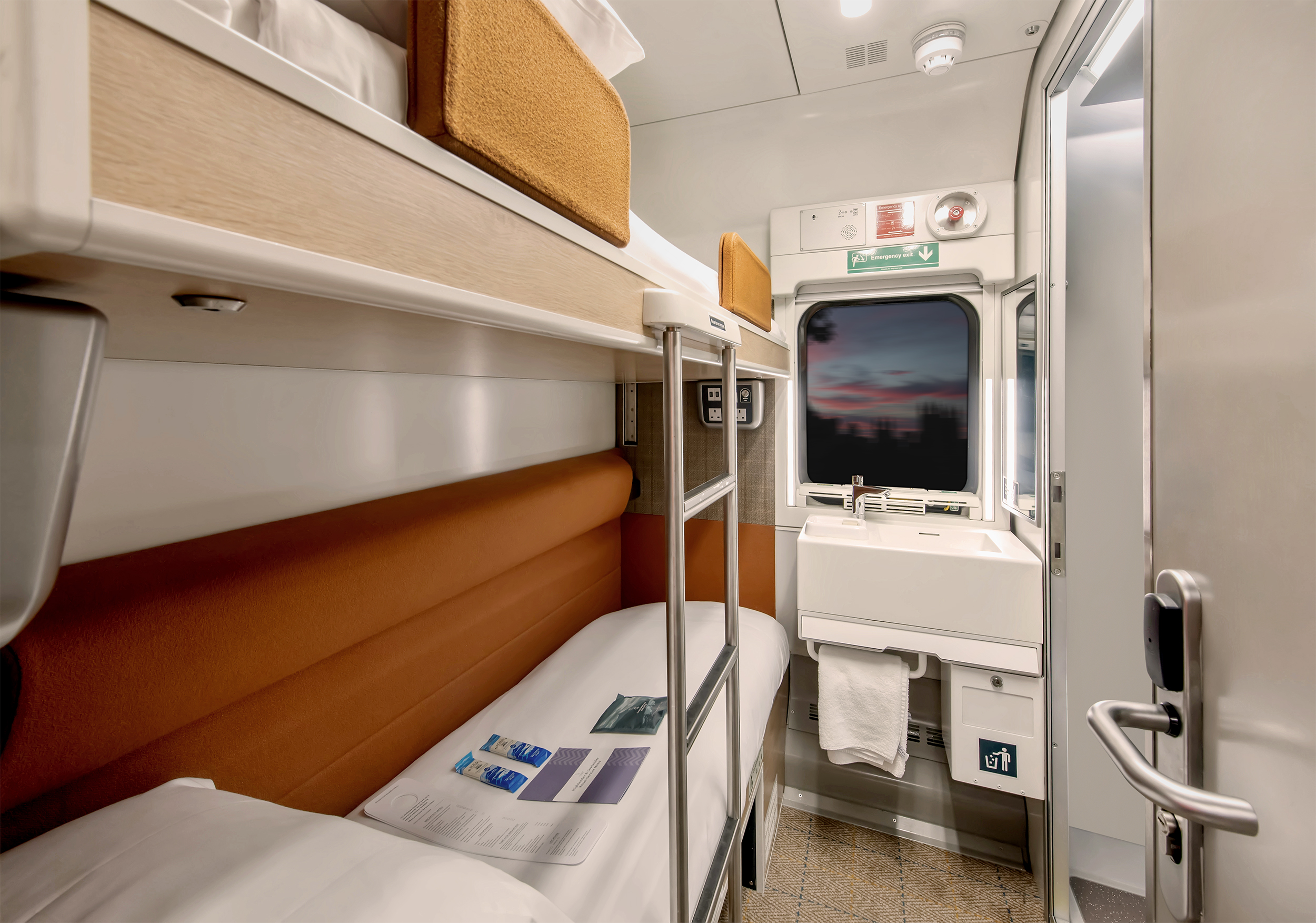 Interior view of a Caledonian Sleeper Room. The sunset can be seen from the window. 
