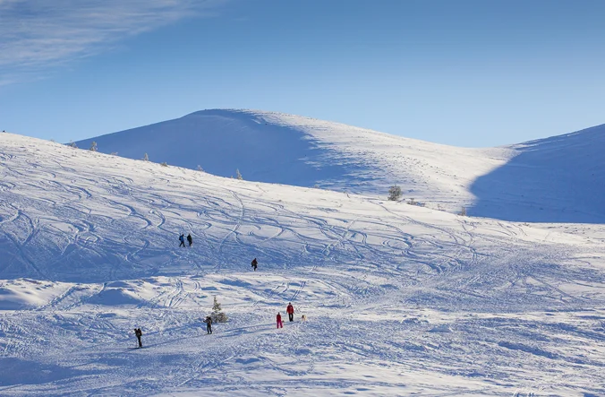 Snow on Cairngorm mountains with people skiing