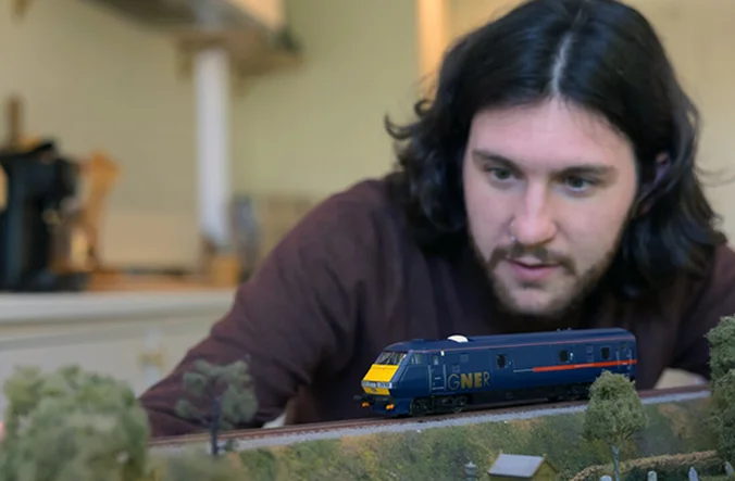 Man overlooking the model railway, focussing on the train.