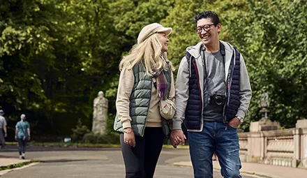 Couple walking through Kelvingrove park.