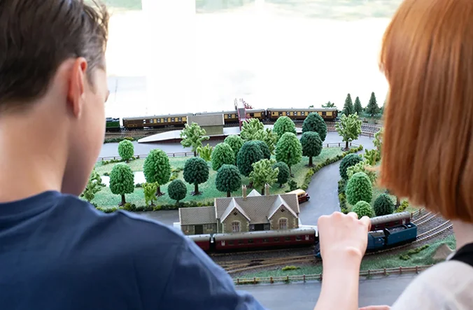 Man and woman moving their Hornby train onto the tracks of their model railway.