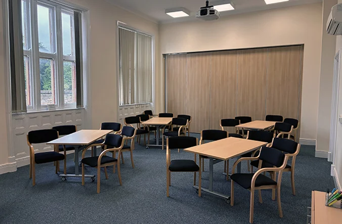 Room set up with 4 desks with chairs surrounding each desk.