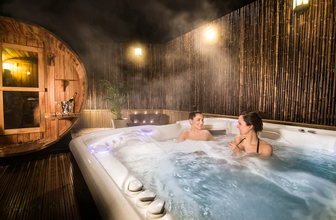 Couple enjoying an outdoor hot tub at Thainstone House.