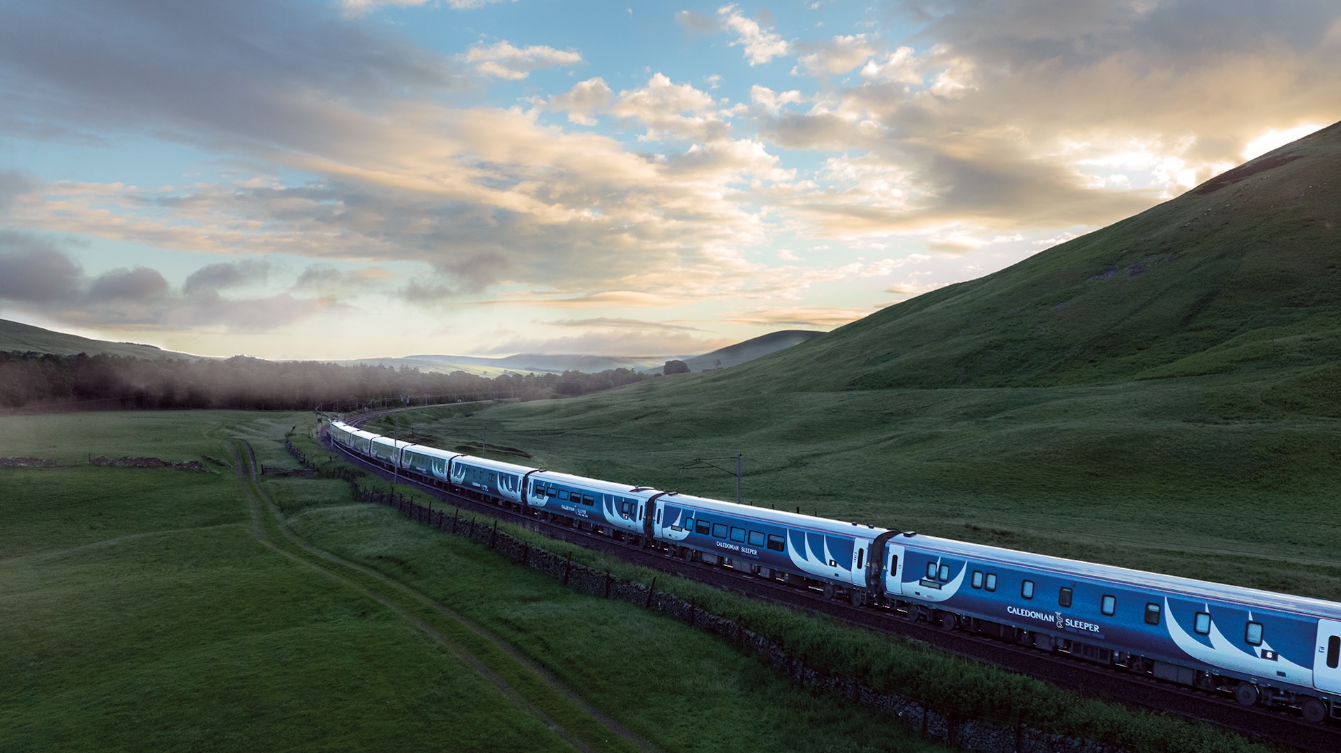 Aerial view of the Caledonian Sleeper Train travelling through the countryside. 