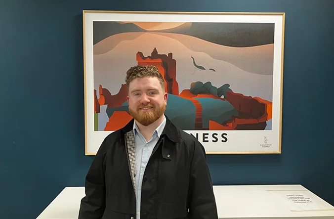 Gentleman standing in front of a Inverness poster.