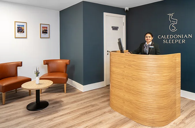 Representative of Caledonian Sleeper smiling at Guest Lounge.