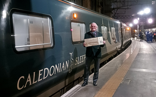 Caledonian Sleeper host holding a Golden Ticket